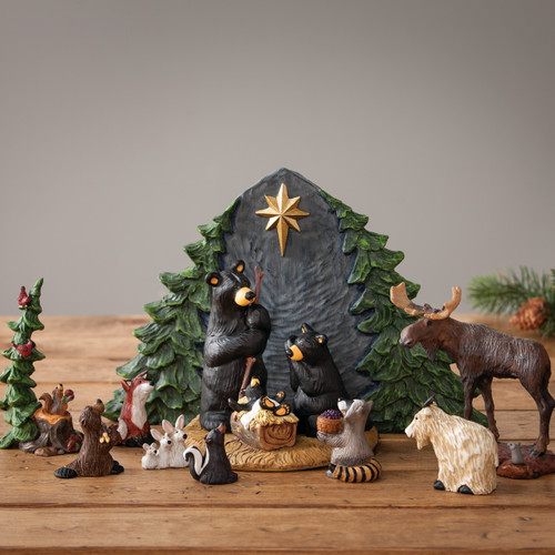 Black bear manger scene - small animal figurines surrounding them and grey manger with green branches - wooden background