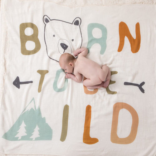 Little baby laying naked on large white blanket that says 'born to be wild' in blue/orange letters