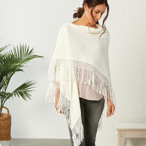 Front view of brunette woman in cream shawl against grey jeans