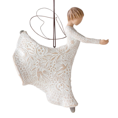 Right view of figure in cream dress carved with natural patterns in ballet pose with hands out and leg up behind her, wire wings on back and ornament hook on head