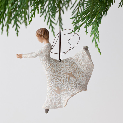 brunette angel ornament in white dress with hands out hanging from green tree