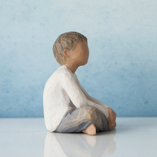 Side view of young boy figurine in white shirt and blue jeans