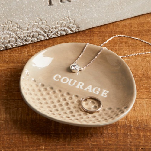 small tan ceramic jewelry dish reading Courage with necklace and ring on it