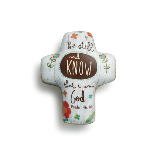 White cross figurine with 'be still and know that I am God' printed in brown around flower print