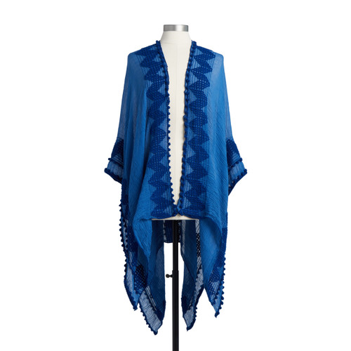 A bright dark blue Textured Duster  with a pom pom border, and a chevron pattered woven into the outsides of the piece. Placed on an ivory and black mannequin.