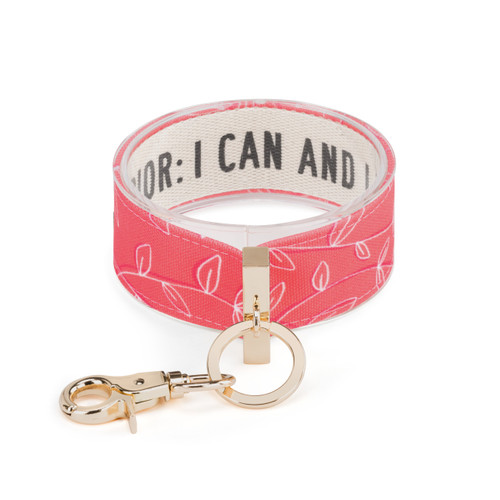 An expanded pink and white leaf print wrist strap with gold metal accents. Inside reads "Warrior: I can and I will".