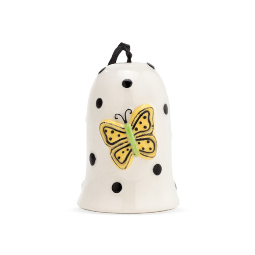 A black and white polka dotted Heartful Home Bell" with a yellow and green butterfly in the center, a chime that reads "happy", and a black ribbon string. Set flat on a white surface."