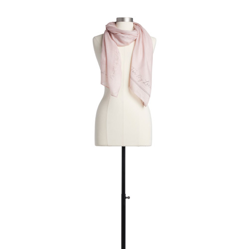 A light pink scarf with a sentimental message in gray script. Placed on an ivory and black mannequin.