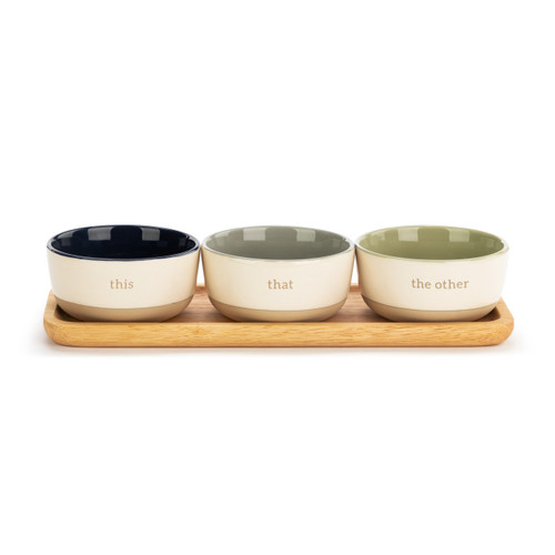 A set of three ivory bowls, each with a brown base. One reads the other" with a green center. One reads "that" with a gray center. One reads "this" with a dark blue center. All placed on a wooden tray."