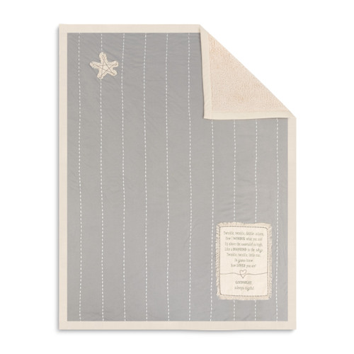 A soft gray baby blanket with thin white stripes, a star patch, a sentimental message patch, and a beige lining. With the top right corner folded over.