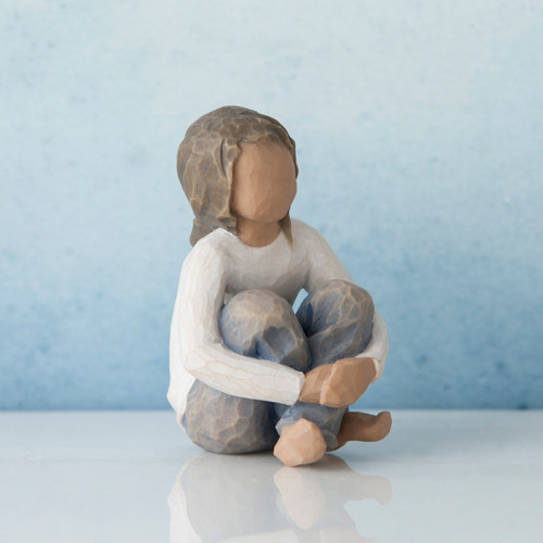 Sitting brunette girl figurine in white shirt and jeans - blue background