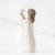 Small brunette girl figurine in white dress facing away holding up white bird
