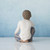 Back view of young boy figurine in white shirt sitting down