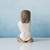 Back view of brunette girl figurine in white shirt kneeling down