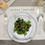 white ceramic place setting with salad on small plate on top of gray placemat with pockets for silverware