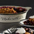 white ceramic pie dish with Made for You written on the side in black holding blueberry crumble surrounded by plates of it