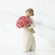 Front view of brunette girl figurine in white dress holding pink roses