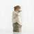 Small girl figurine wearing white dress holding baby - side view - sitting on brown rock