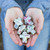 Hands holding out five small white cross figurines