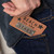 detail shot of someone putting metal plaque reading reach for the stars into their jeans pocket