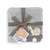 gray blanket with Noah's Ark decals on it folded up wrappes in a ribbon with attached product label