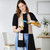 woman with black and brown and white patterned towel scarf pouring wine in kitchen