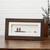 Dark wooden photo frame with white center and pebbles with beach chairs in the center