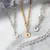 A close up image of an assortment of jewelry pieces, two silver and one gold, each with a circular pendant with either a cross, star, or dove stamped in the center. Each lined with various metallic colored beads. Placed on a marble countertop.