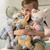 A young boy holding four plush animals. A pink kitty, an orange giraffe, a brown sloth, and a gray elephant.