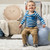 A young boy playing in a nursery setting. Appears to be sitting on a blue "Earth Pour" ottoman.