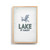 A graphic image of a blue Adirondack chair with "Lake It Easy" written below on a light gray background. The image is in a light wood frame.