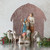 Close front view of mary and joesph figurines around white sheep figurines - brown paper barn behind them