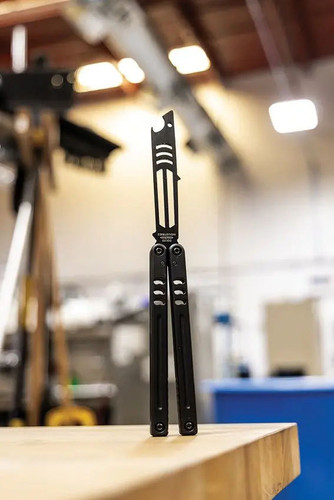 Squid Industries Mako V5 410 Inked Balisong Butterfly Trainer standing open balanced on black-coated handles on a work table Squid Industries Mako V5 410 Inked Balisong Butterfly Trainer standing open balanced on black-coated handles on a work table