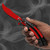 Red butterfly balisong trainer held in hand showing open scimitar style trainer blade