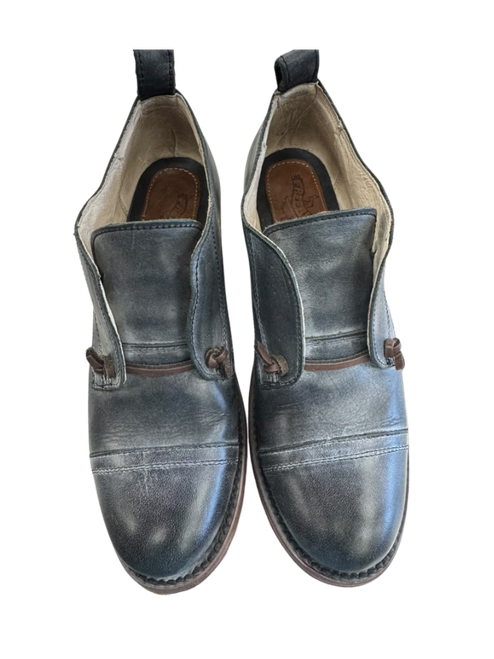 Vist Large View of Product Image Which is Frye men’s dark black leather slip-on shoes with cap-toe stitching, brown side accents, rear pull tabs, and visible gently used wear.