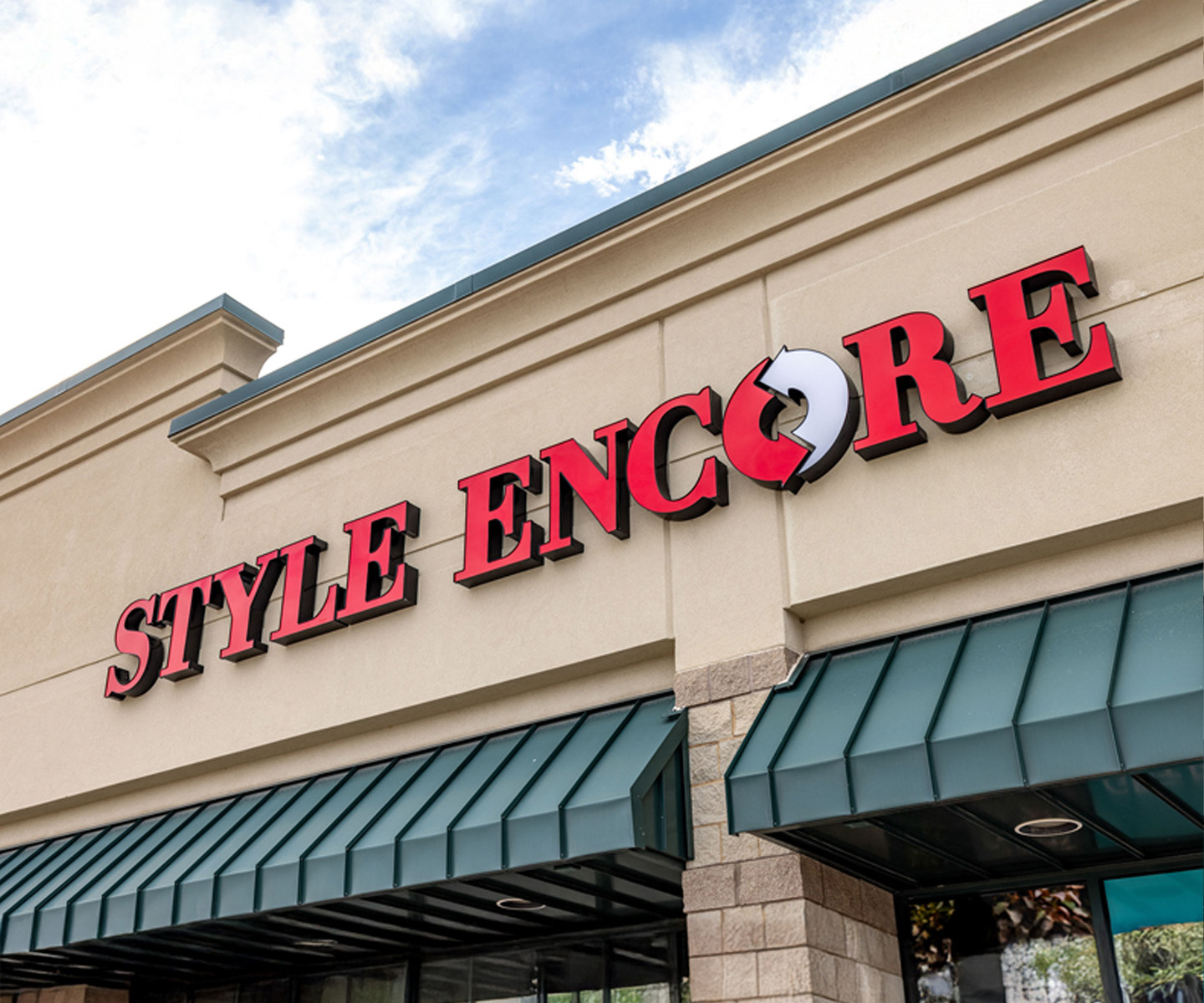 Outside of a Style Encore storefront with an open sign on and clothing organized inside