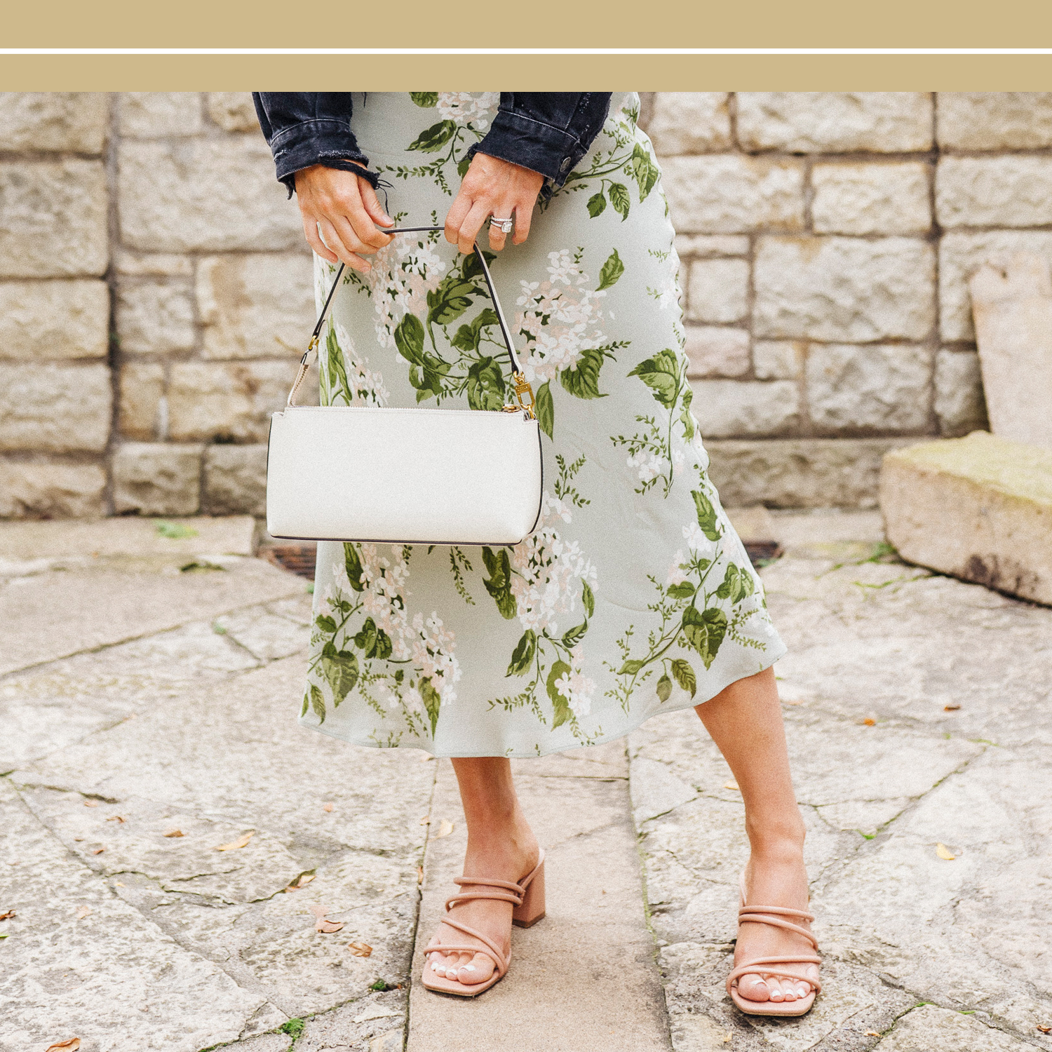 Woman in floral dress and heels holding a purse