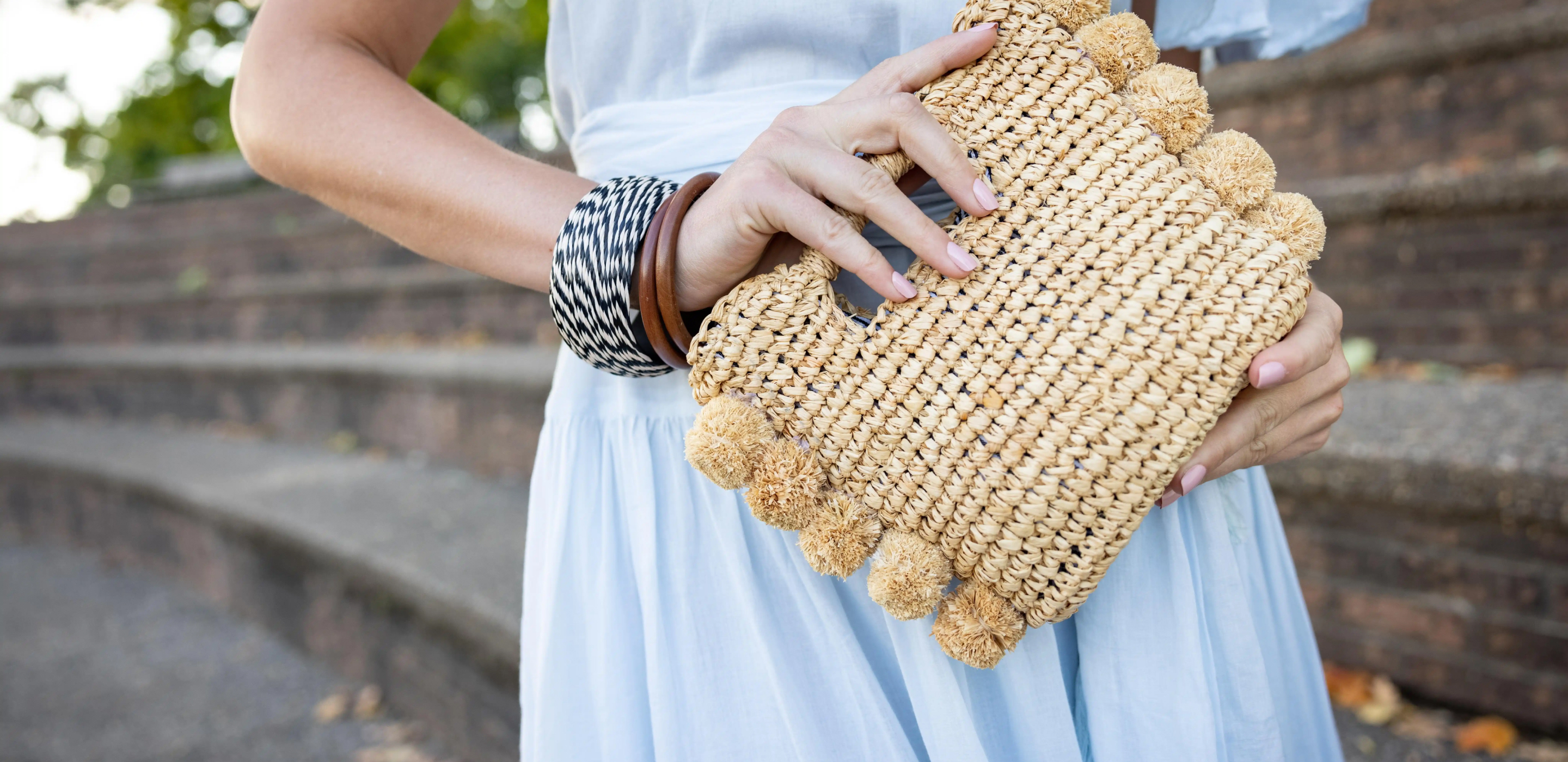 person holding a clutch purse and wearing black and white braclets