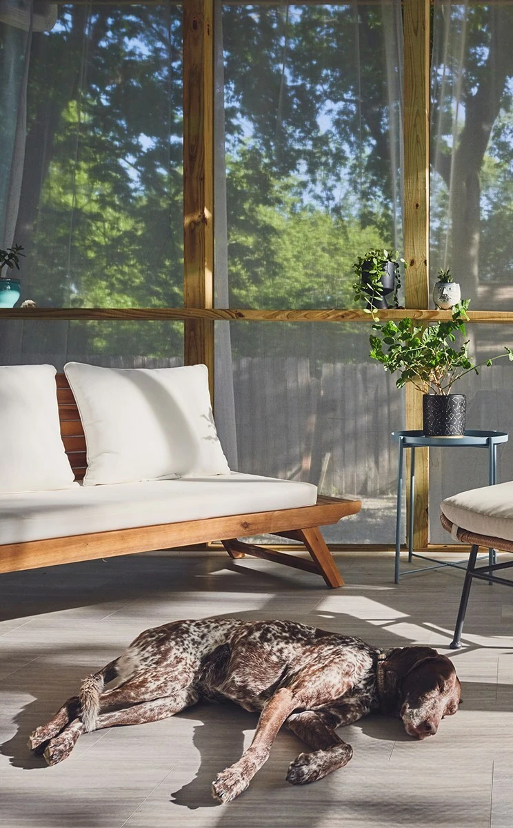 Interior of a screened porch with wood framing, mesh panels, and outdoor furniture