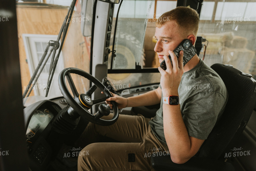 Young Farmer Talks on Phone in Tractor Cab 7551