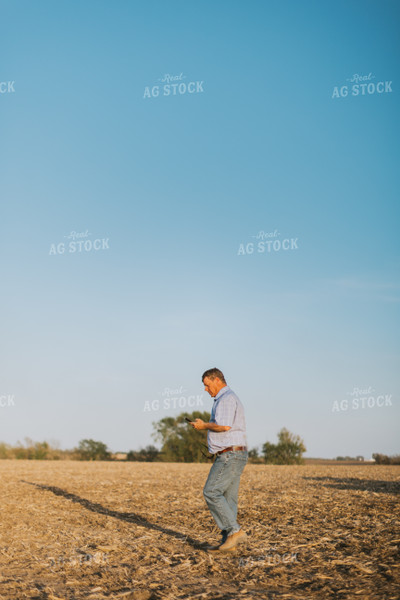 Farmer Walks in Field While Looking at Phone 7707