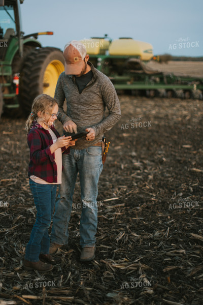 Farmer using Tablet in Field by Planter with Daughter 8262
