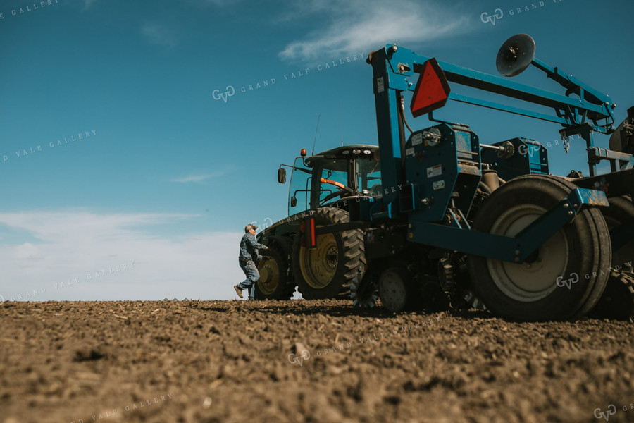 Farmer Climbing into Tractor with Planter 4101