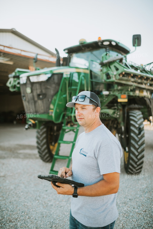 Farmer Looking at iPad with Sprayer in Background 6250