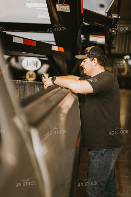 Farmer Looks at Phone While Leaning on Truck Bed 7576