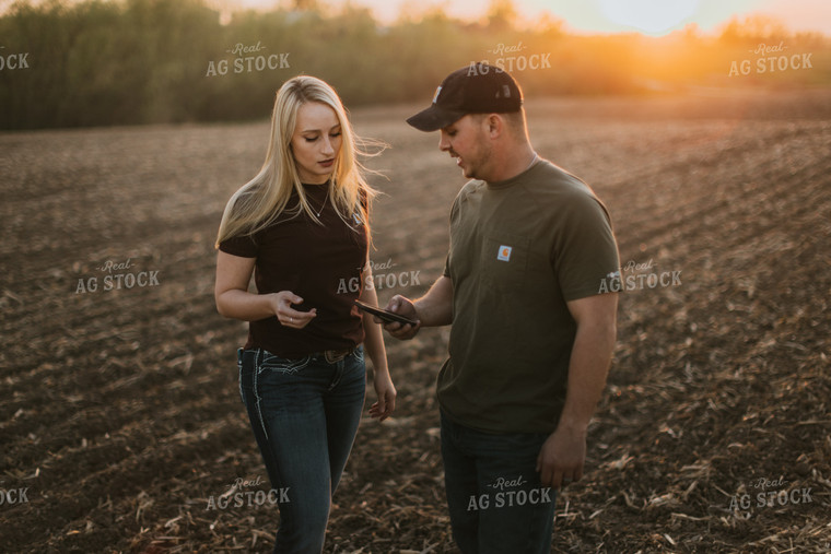 Young Couple Look at Phone in Field at Sunset 7728