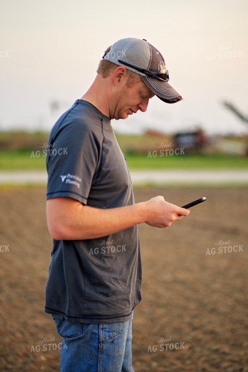 Farmer Looks at Phone in Field 93209