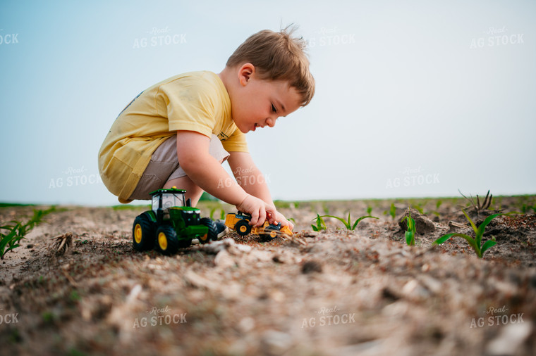 Young Boy Plays with Farm Toys in the Soil of a Freshly Planted Corn Field 56664