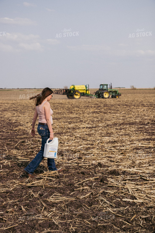 Female Farmer Carries Pesticide Concentrate in Field with Sprayer in Background 67285