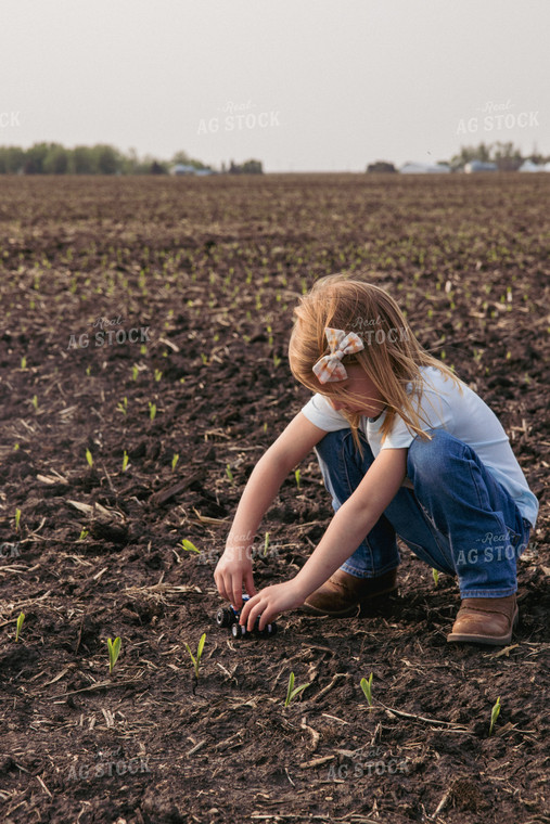 Farm Kid Plays with Toy Tractor in Emerging Corn Field 67291